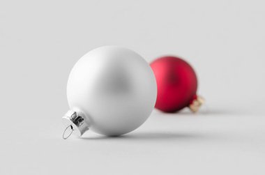 Beyaz ve kırmızı matte Noel topları pürüzsüz gri bir arka planda.