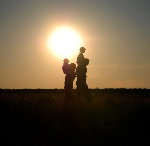 Children on the shoulders of parents go summer evening — Stock Photo, Image