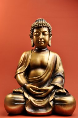 Bronze Buddha Statue Against a Red Orange Background clipart