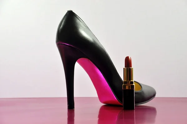 Stilettos à talons hauts noirs et rouge à lèvres sur fond de broche — Photo