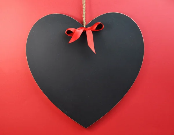 Mensaje en blanco en pizarra de corazón contra un fondo rojo . — Foto de Stock