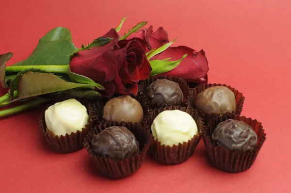 Pralinen und Rosen zum Valentinstag auf rotem Hintergrund. — Stockfoto