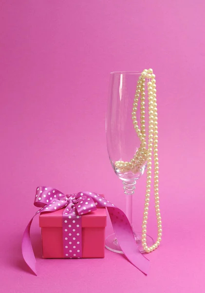 Ženský dárek s polka dot růžovou stuhu a champagne skla s perlami — Stock fotografie