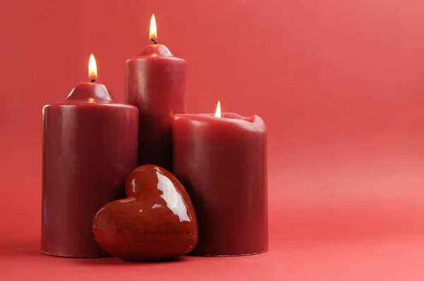Three romantic red lit candles against a red background with copy space, horizontal. — Stok fotoğraf