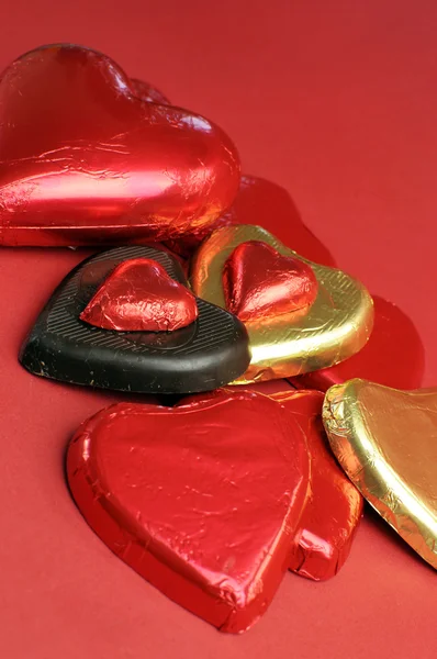 Pralinen in roter und goldener Herzform - vertikale Nahaufnahme. — Stockfoto