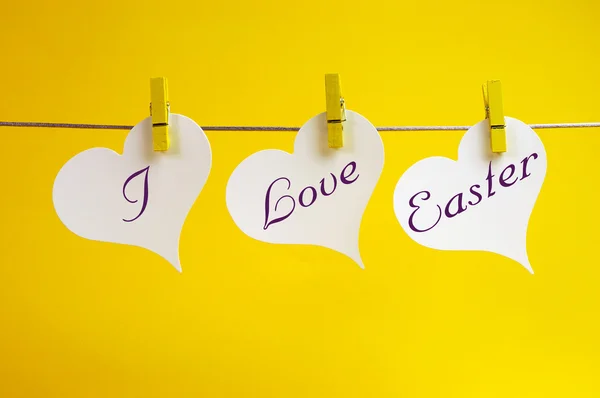 Ich liebe Osterbotschaft geschrieben über 3 Herz-Tags, die vor gelbem Hintergrund an der Zeile hängen. — Stockfoto