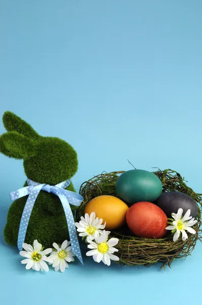 Thème bleu Joyeux Pâques nature morte avec lapin herbe avec des œufs de couleur arc-en-ciel dans un nid — Photo