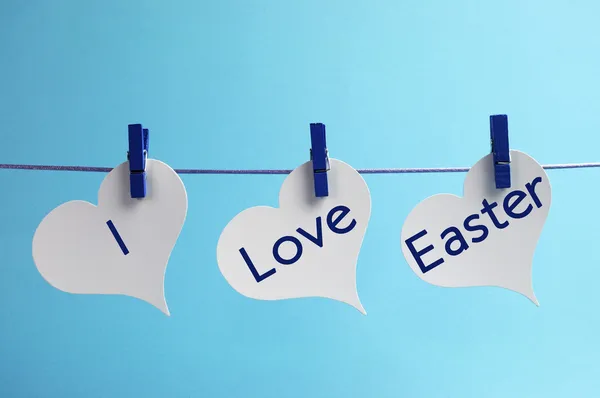 Ich liebe Osterbotschaft geschrieben über 3 Herz-Tags, die vor blauem Hintergrund an der Zeile hängen. — Stockfoto