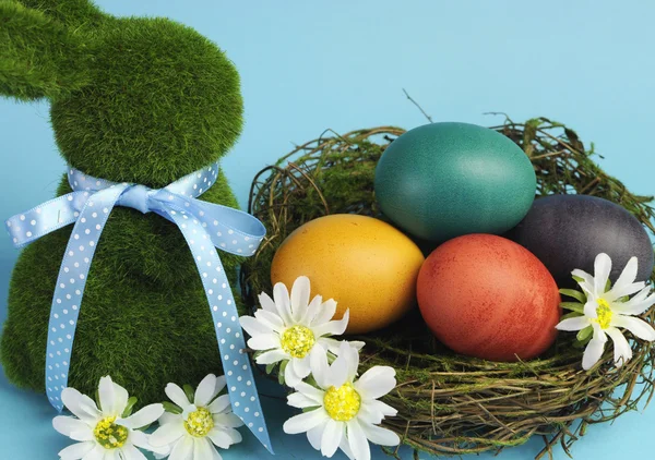 Blå tema Glad påsk Stilleben med gräs kanin med rainbow färg ägg i ett rede — Stockfoto