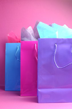 renkli pembe mor ve mavi alışveriş torbaları, kadınsı pembe bir arka plan üzerine açık görünüm.