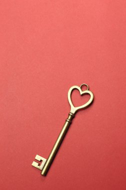 kırmızı zemin üzerine bir altın kalp anahtar. kopya alanı ile dikey.