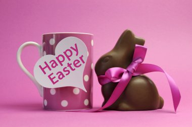 Mutlu Paskalya pembe polka dot kahve veya çay bardağı beyaz kalp şekli hediye etiket işareti ve çikolata bunny ile mutlu Paskalya mesaj ile pembe kurdele ile