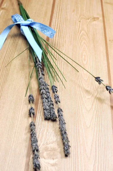 Zweige Lavendelblüte gebunden in blauem Tupfen-Band für Aromatherapie, Gesundheit oder Kräuterstrauß, auf Holztisch - senkrecht. — Stockfoto