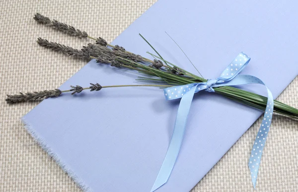 Takjes van lavendel bloem gebonden in blauwe polka dot lint voor aromatherapie, gezondheid of kruiden boeket, op blauwe servet. — Stockfoto