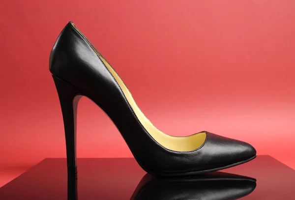 Zwarte stiletto vrouwelijke hoge hak schoen op rode achtergrond — Stockfoto