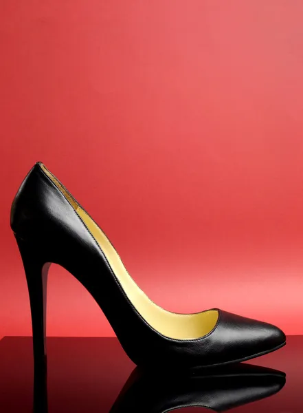 Zapato de tacón alto negro con tacón alto sobre fondo rojo - vertical con espacio de copia para tu texto aquí . —  Fotos de Stock