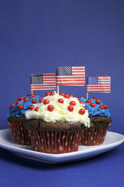 Fourth 4th of July party celebration with red, white and blue chocolate cupcakes on white heart plate and USA American flags