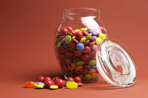 Glass Jar full of bright colorful lollies and candy with closed lid for Christmas or Halloween treats.