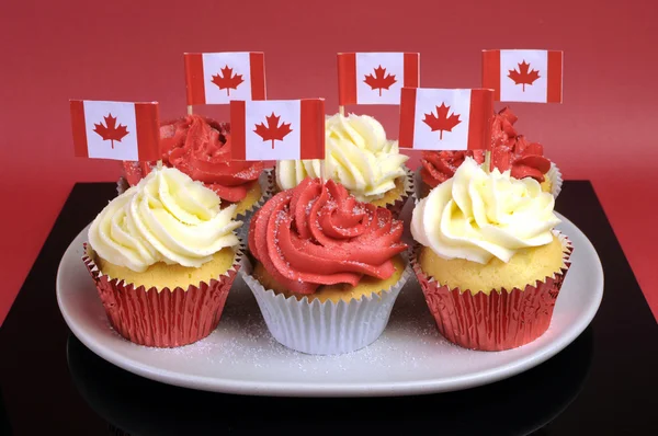 Cupcake rossi e bianchi con bandiere nazionali in foglia d'acero canadese su uno sfondo rosso per la Giornata del Canada o le festività nazionali canadesi. Primo piano . — Foto Stock