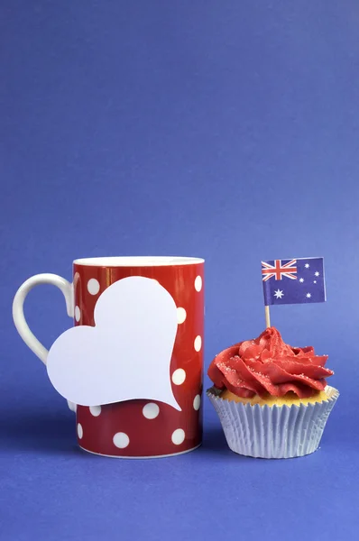 Australische thema rood, wit en blauw cupcake met nationale vlag en rode polka dot koffiemok voor Australië dag, anzac dag of nationale feestdag tegen een blauwe achtergrond. verticale met kopie ruimte. — Stockfoto