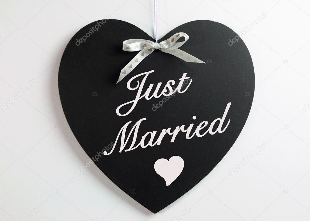 Heart shape blackboard with white hearts ribbon against a white background with Just Married message for weddings or honeymoons.