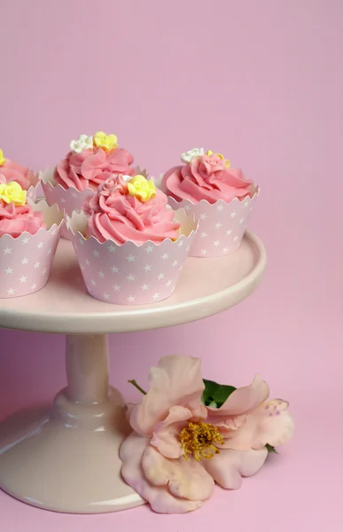 Hermosos cupcakes decorados de color rosa en soporte de pastel rosa para cumpleaños, boda o ocasión de evento especial femenina. Vertical con rosa rosa flor . —  Fotos de Stock