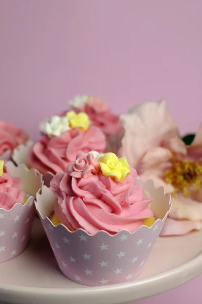 Vacker rosa dekorerade cupcakes på rosa tårta står för födelsedag, bröllop eller kvinna speciell händelse tillfälle. vertikal på nära håll med bokeh. — Stockfoto