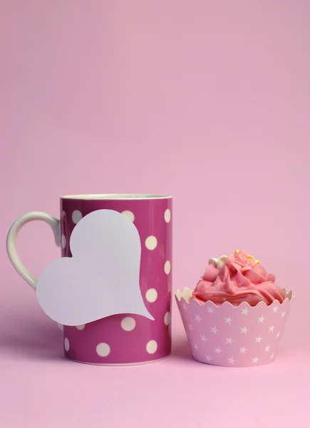 Caneca de café de bolinhas rosa com cupcake rosa e etiqueta de presente em forma de coração branco em branco para o seu texto aqui, para aniversário feminino, dia das mães ou evento especial da ocasião. Vertical com espaço de cópia . — Fotografia de Stock