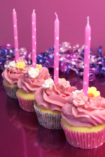 Pinkfarbene Geburtstagskuchen mit gepunkteten Kerzen vor rosa Hintergrund. vertikal mit seichtem Fokus auf zweiten Cupcake. — Stockfoto