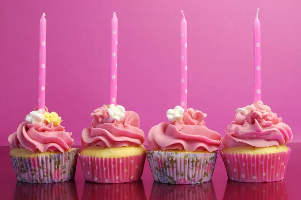 Pink birthday cupcakes with polka dot candles against a pink background. — Stock Photo, Image