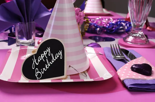 Decoraciones de mesa de fiesta temática rosa y púrpura con primer plano de sombrero de fiesta y feliz cumpleaños mensaje de corazón . — Foto de Stock