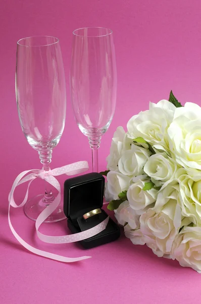 Bruiloft bruids boeket van witte rozen op roze achtergrond met pair champagne fluit bril en gouden trouwring in zwarte sieraden doos. verticale. — Stockfoto