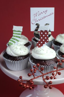 Noel beyaz buzlanma ile kırmızı kadife çikolata cupcakes ve pembe kek standı üzerinde kırmızı ve yeşil şenlikli süslemeleri süslü