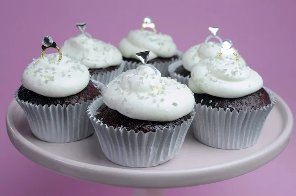 Matrimonio tema cioccolato rosso valvet cupcakes su stand rosa con anelli di diamanti decorazioni nuziali — Foto Stock