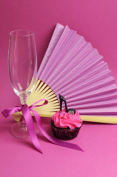 Cupcake partido rosa con zapato de tacón alto stilleto negro con copa de champán, abanico y chocolates —  Fotos de Stock