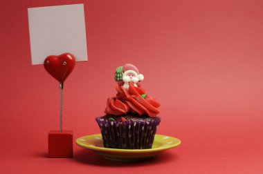 Kırmızı santa Noel şenlikli cupcake yeşil plaka üzerinde mor polka dot wrapper olarak