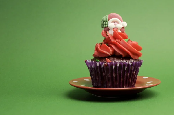 Christmas Cupcake in purple polka dot wrapper with red frosting and santa decoration — Stock Photo, Image