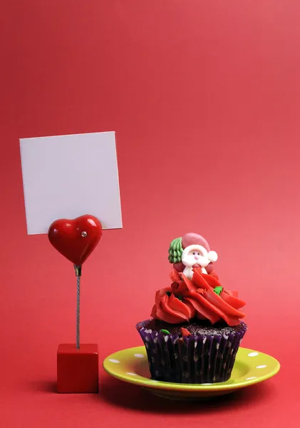 Κόκκινο santa Χριστούγεννα εορταστική cupcake σε μωβ πουά περιτύλιγμα στο πράσινο πιάτο σε κόκκινο φόντο — Φωτογραφία Αρχείου