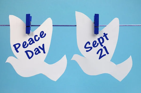 Peace Day message written across white doves hanging from pegs on a line — Stock Photo, Image