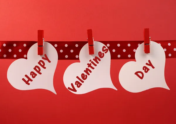 Feliz Dia dos Namorados mensagem saudação escrita através de tags de coração branco pendurado em pinos vermelhos em uma linha — Fotografia de Stock