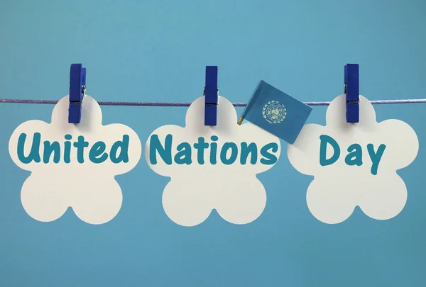 Mensagem de saudação do Dia das Nações Unidas escrita em etiquetas brancas com bandeira pendurada em pinos azuis em uma linha — Fotografia de Stock