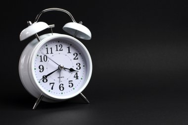 Klasik beyaz alarm saat siyah arka plan üzerinde geçiyor