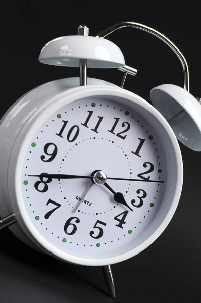 Klassieke witte alarm tikkende klok op zwarte achtergrond — Stockfoto