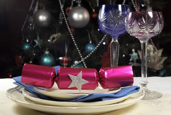 Linda mesa de Natal na frente da Árvore de Natal, com rosa e azul copos de vinho de cristal de haste longa e decorações — Fotografia de Stock