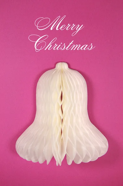 Christmas greeting with white bell paper ornament against a pink background — Stock Photo, Image