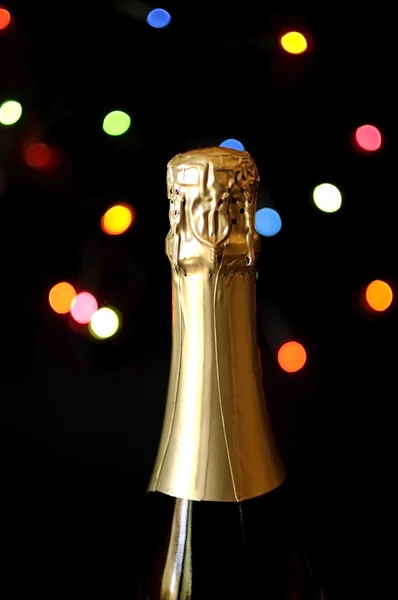 Feliz Año Nuevo botella de champán de cerca contra las luces bokeh sobre fondo negro , — Foto de Stock