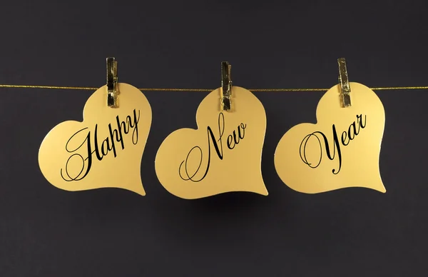 Happy New Year message greeting text on gold hearts hanging from pegs on a line — Stock Photo, Image