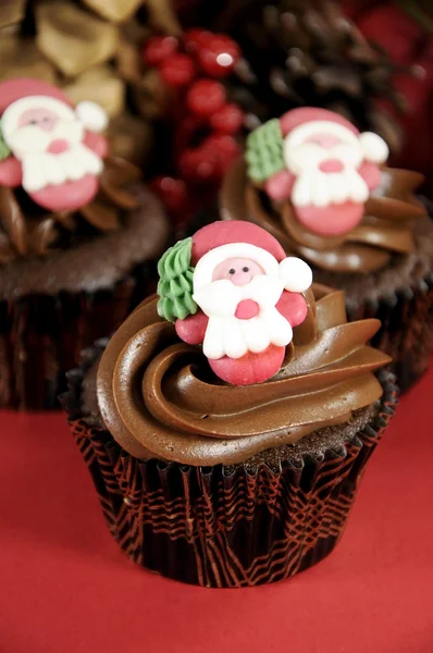 Feliz Navidad cupcakes de chocolate con caras de Santa contra fondo rojo festivo . — Foto de Stock