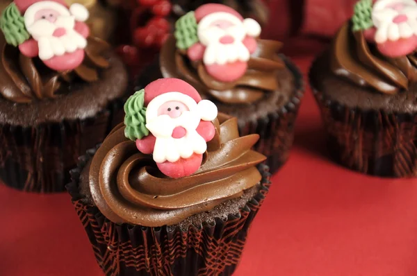 Frohe Weihnachten Schokolade Cupcakes mit Weihnachtsgesichtern vor rotem festlichen Hintergrund. — Stockfoto
