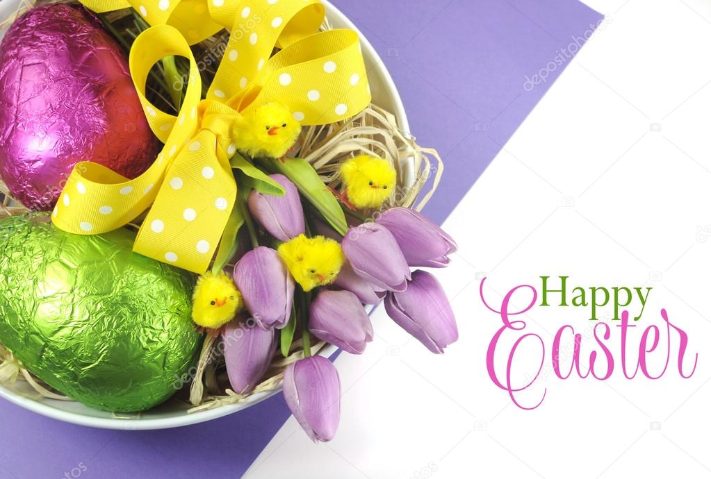 Happy Easter basket of colorful pink and green foil wrapped eggs and pink purple tulips with chicks